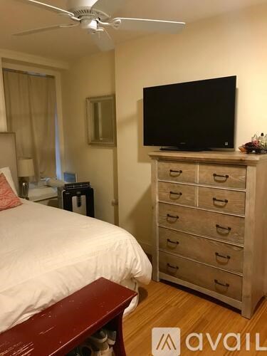 A bedroom with a bed, dresser, and television.
