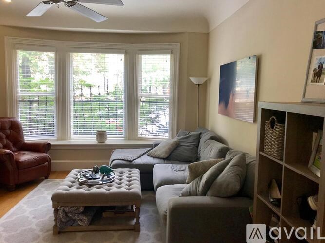 A living room with a red leather chair, a grey sofa, and a coffee table with a decorative item on it.