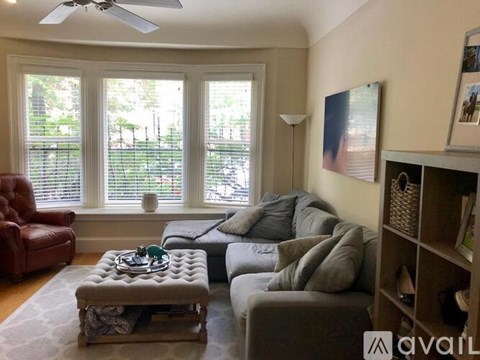 A living room with a red leather chair, a grey sofa, and a coffee table with a decorative item on it.