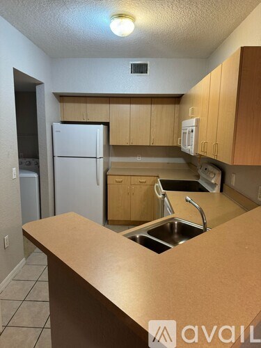 A kitchen with a white refrigerator and wooden cabinets.
