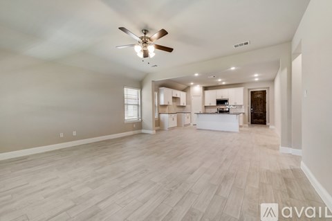 A spacious living room with a ceiling fan and lighting fixtures.