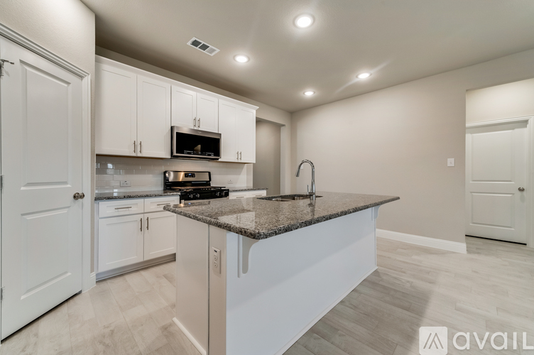 A kitchen with white cabinets and a granite countertop.