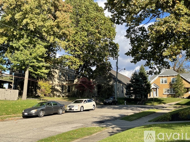 Two cars parked on a street with trees and houses in the background.