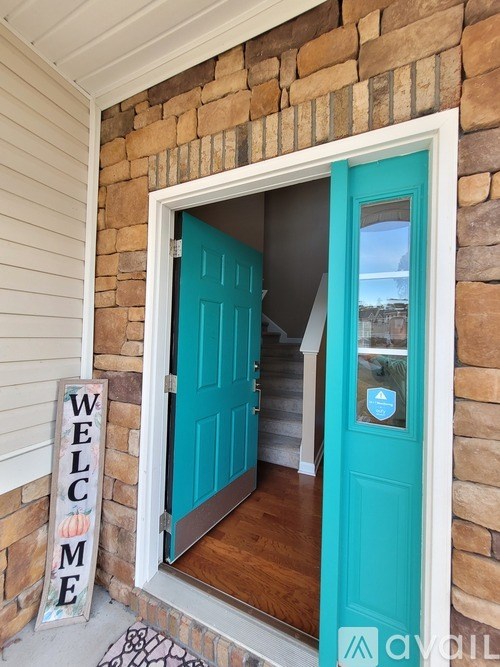 A turquoise door with a glass window and a sign that says "Welcome".