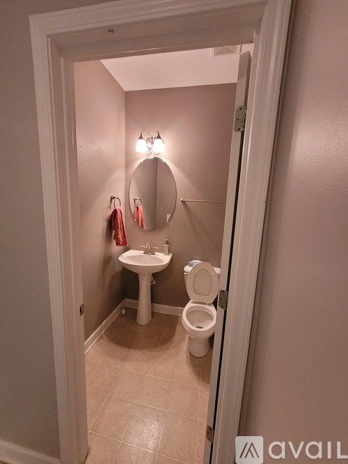 A bathroom with a toilet, sink and mirror.