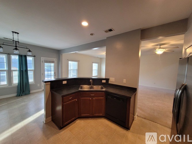 A kitchen with dark brown cabinets and a black countertop.