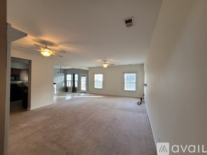 A spacious living room with a carpeted floor and a ceiling fan.