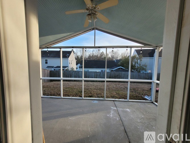 A patio with a fan and a view of a house across the way.