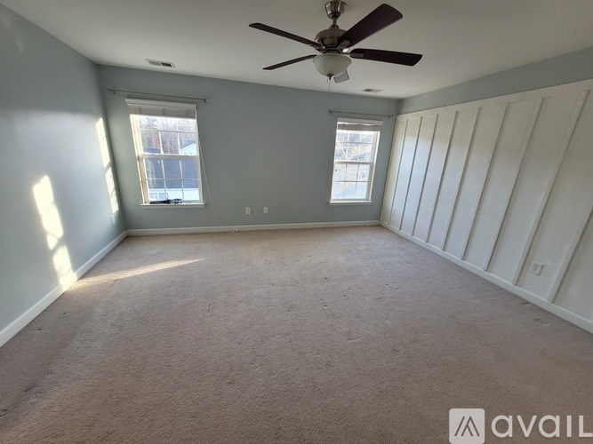 A room with a ceiling fan and two windows.