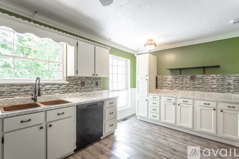 A kitchen with white cabinets and a stone backsplash.