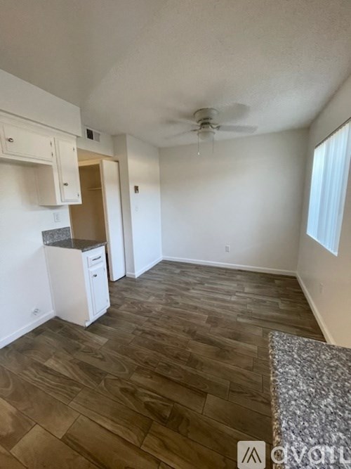 A room with a ceiling fan and wood flooring.