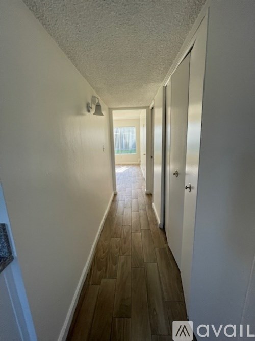 A long hallway with wood floors and white walls.