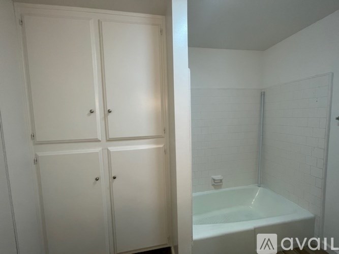 A white bathroom with a tub and cabinets.