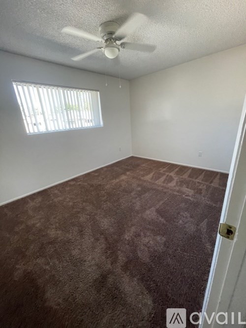 A room with a carpeted floor and a ceiling fan.