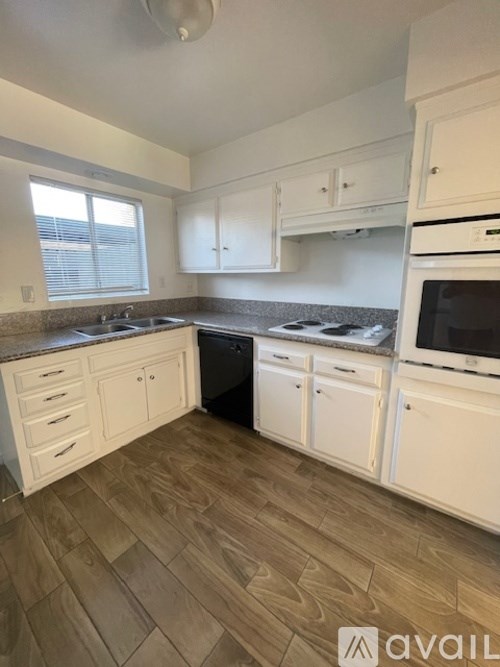 A kitchen with white cabinets and a wooden floor.