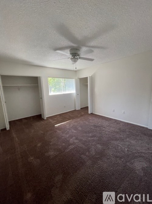 A room with a ceiling fan and carpeted floor.