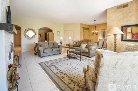 A living room with a grey sofa, a white couch, and a rug with a floral pattern.