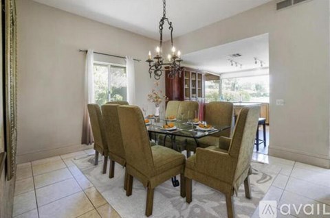 A dining room with a table set for six and a chandelier hanging from the ceiling.