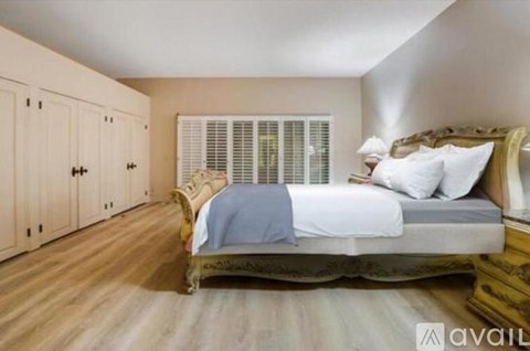 A bedroom with a large bed and wooden floors.