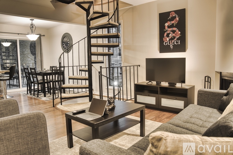 A living room with a spiral staircase and a Gucci poster on the wall.