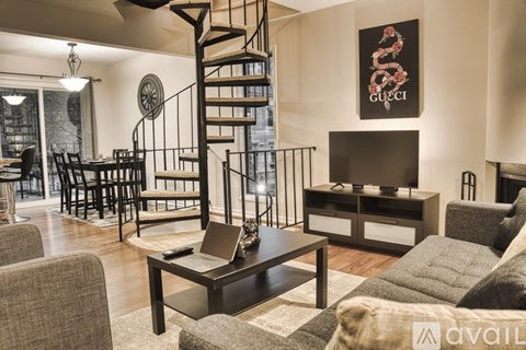 A living room with a spiral staircase and a Gucci poster on the wall.
