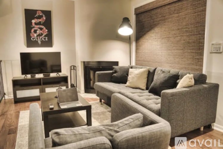 A living room with a grey couch and a Gucci poster on the wall.