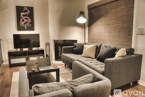 A living room with a grey couch and a Gucci poster on the wall.