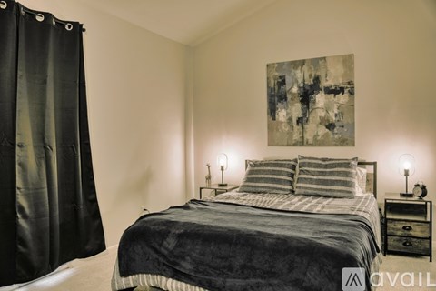 A bedroom with a large bed and a painting on the wall.
