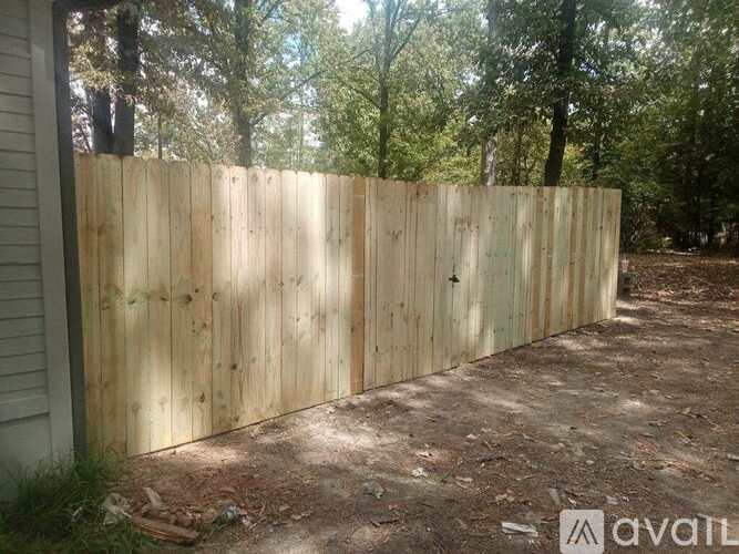 A wooden fence in a backyard with trees in the background.
