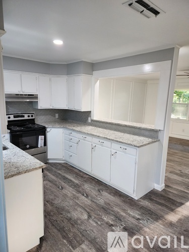 A kitchen with white cabinets and a granite countertop.