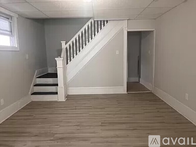 A room with a staircase and a door leading to another room.