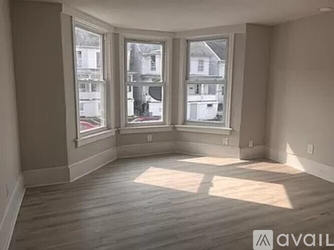 A room with wooden floors and large windows overlooking a street.