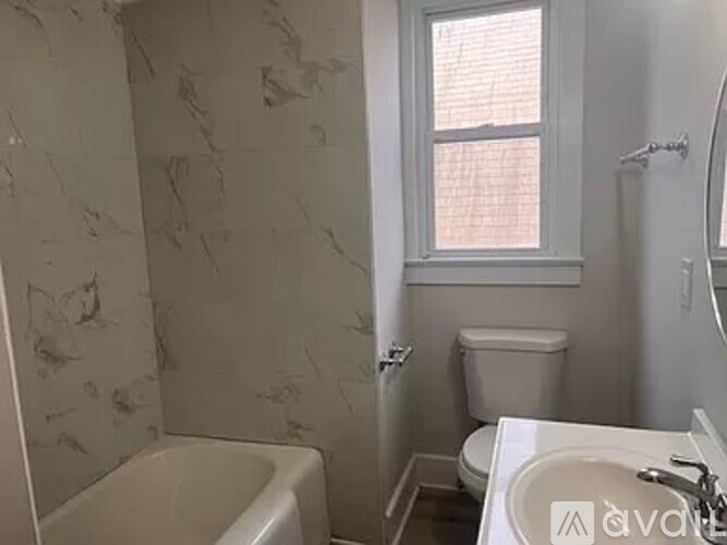 A bathroom with a marble wall and a white toilet.