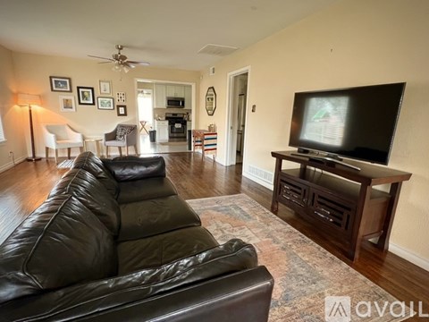 A living room with a black leather couch and a television on a wooden stand.