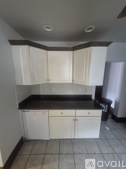 A kitchen with white cabinets and a black countertop.