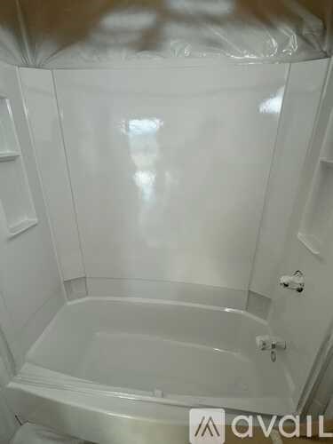 A white bathroom with a bathtub and a towel rack.