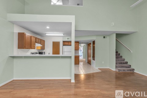 A spacious living area with a kitchen and stairs leading to another room.