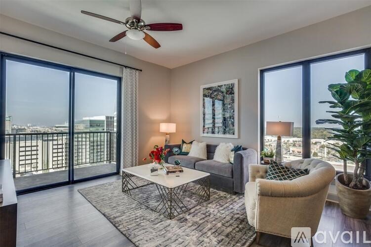 A living room with a large window, a sofa, a coffee table, and a potted plant.