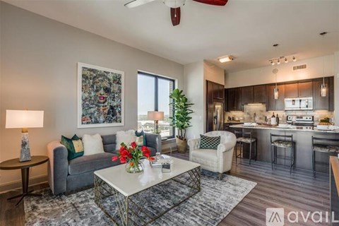 A living room with a grey couch, a white coffee table, and a painting on the wall.