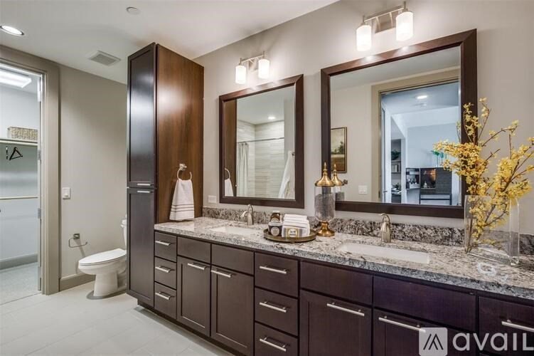 A bathroom with brown cabinets and a marble countertop.