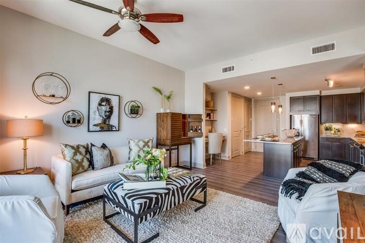 A living room with a white couch, a zebra print coffee table, and a ceiling fan.
