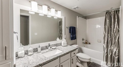 A bathroom with a large mirror, a sink, a toilet, and a shower.