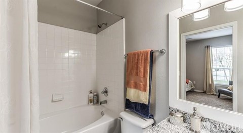 A bathroom with a white tub and a towel hanging on the rack.