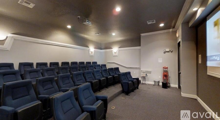 A row of blue chairs are arranged in a room with a screen on the wall.