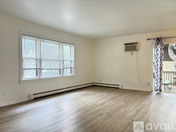 A spacious room with wooden floors and a large window.