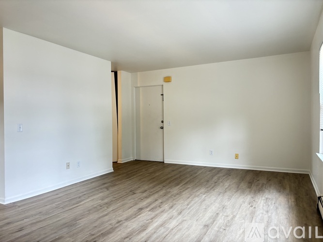 A room with a wooden floor and white walls is available for rent.