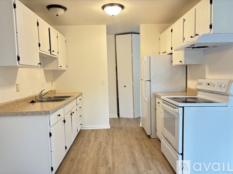 A kitchen with white cabinets and appliances.