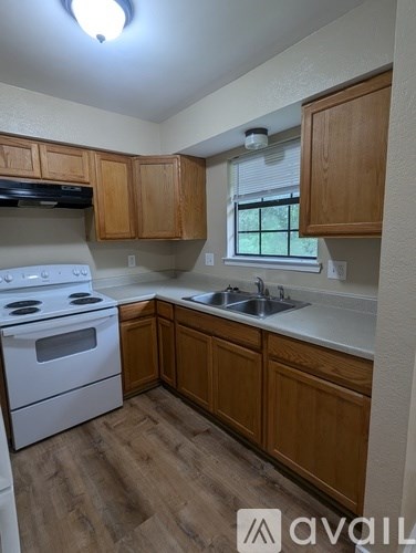 A kitchen with wooden cabinets and a white stove top oven.