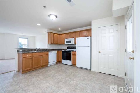 A spacious empty room with a carpeted floor and white walls.