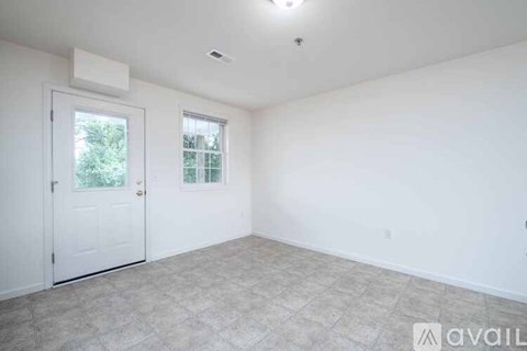 A white room with a window and a carpeted floor.